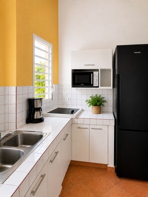 Eine moderne Küche mit weißen Schränken, einem schwarzen Kühlschrank, einer Mikrowelle und einer Kaffeemaschine.