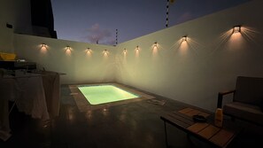 Un espace piscine sur le toit, comprenant un jacuzzi, des sièges et un éclairage mural.
