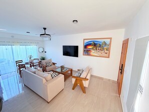 A modern living room with a sofa, armchair, coffee table, and a TV mounted on the wall. - Private Pool Villa. 3BR Near Bávaro Beach. Sleeps 8 (Punta Cana)