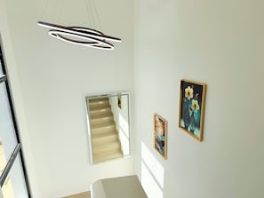 A staircase with a glass railing, a modern pendant light fixture, and two framed artworks on the wall. - Private Pool Villa. 3BR Near Bávaro Beach. Sleeps 8 (Punta Cana)