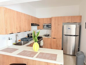 Une cuisine moderne dotée de meubles en bois, d’appareils électroménagers en acier inoxydable, d’un four à micro-ondes et d’un réfrigérateur.