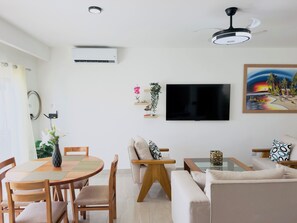A modern living room with a dining area, a flat-screen TV mounted on the wall, and a ceiling fan. - Private Pool Villa. 3BR Near Bávaro Beach. Sleeps 8 (Punta Cana)