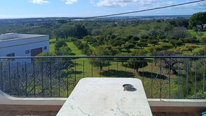 A balcony with a table and a view of a green landscape and distant buildings. - T2 Magnificent Views (Faro)