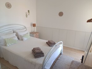 A bedroom with a bed, pillows, a bedside table with a lamp, and a wall decoration. - T2 Magnificent Views (Faro)