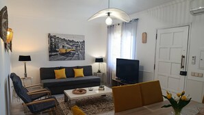 A living room with a sofa, armchairs, a coffee table, a TV, and a painting on the wall. - T2 Magnificent Views (Faro)