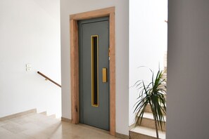 A hallway with a grey door, a wooden frame, a brass handle, and a potted plant. - Vacation rental on Via Jappelli in Abano Terme. Free Wi-Fi (Abano Terme)