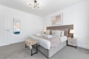 A bedroom with a bed, bedside tables, a mirror, a ceiling light fixture, and a framed artwork on the wall. - Perfect Location near Heathrow & 2 min London Tube (Hounslow)