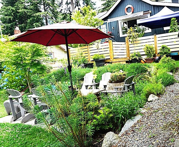 A garden with a red umbrella, outdoor seating, and a wooden fence.