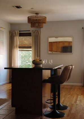 A dining area with a wooden table, two chairs, a bowl of fruit, and a mirror on the wall. - Cozy Traveler's Dream Near NYC & PATH w/ Private Parking (Jersey City)