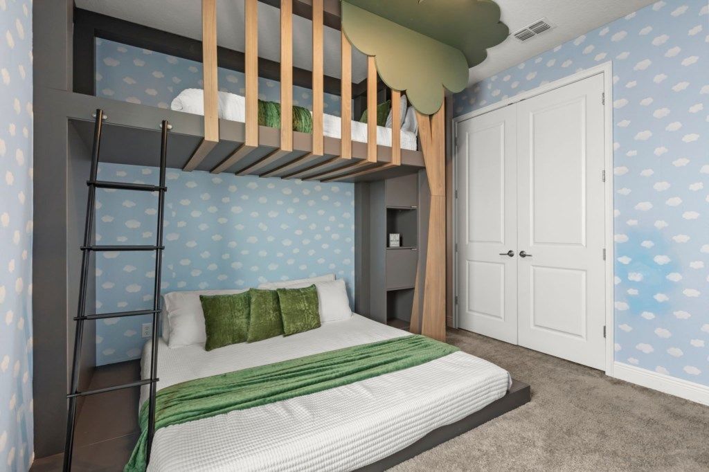 A bedroom with a bunk bed, a ladder, a wardrobe, and a door.