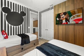 A hotel room with a Mickey Mouse wall decoration, a television, and a door leading to another room. - Bear's Den at Reunion - Luxury 4BD/3BA (836 DM) (Kissimmee)