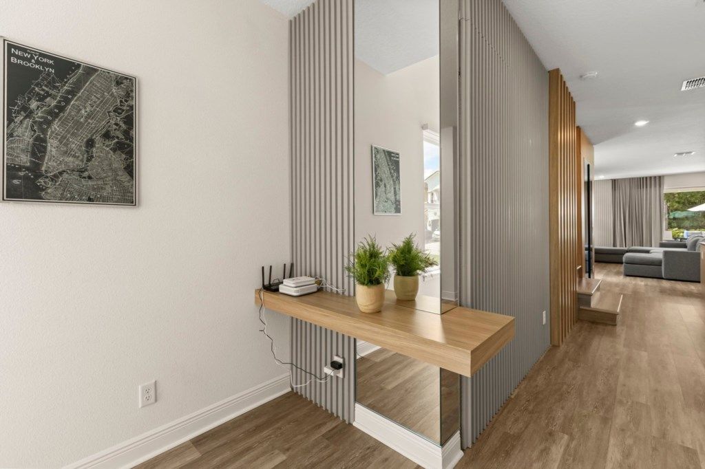 A modern interior with a wooden console table, a map, and a view into a living area.
