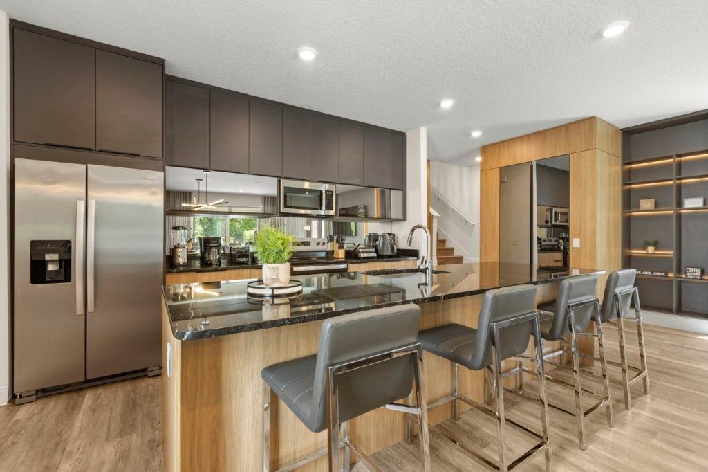 A modern kitchen with a central island, stainless steel appliances, and bar stools.