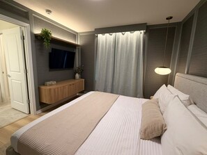 A modern bedroom with a large bed, a TV mounted on the wall, a bedside table, and a hanging light fixture. - Custom Bedrooms 10 BD/8 BA/ Windsor Cay - 15906 CK (Clermont)