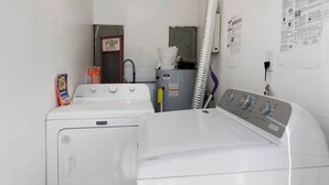 Un área de lavandería con dos lavadoras, un secador y un cuarto de servicio con calentador de agua.