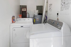 Ein Waschbereich mit zwei Waschmaschinen, einem Trockner und einem Hauswirtschaftsraum inklusive Warmwasserbereiter.