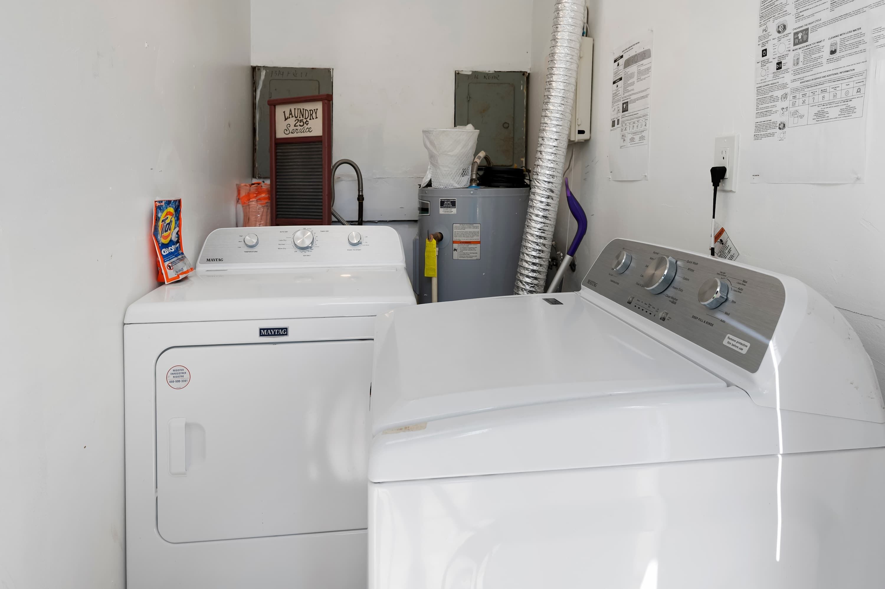 Ein Waschraum mit zwei Maytag Waschmaschinen, einem Trockner und einem Warmwasserbereiter.