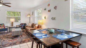 Ein Wohnzimmer mit Sofa, Couchtisch und Esstisch mit Platzsets.