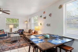 Ein Wohnzimmer mit Sofa, Couchtisch und Esstisch mit Platzsets.