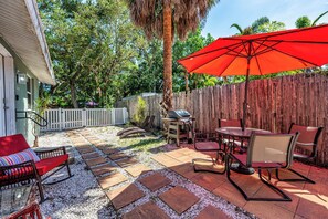A patio with a grill, outdoor furniture, and a red umbrella. - Aeon Suite Bike/Walk Dtwn 2BR, Grill, Patio & Pups (Sarasota)
