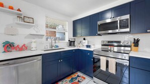 Eine moderne Küche mit blauen Schränken, Edelstahlgeräten und einem farbenfrohen Teppich mit Fischmuster.