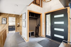 A modern interior with a wooden staircase, a black door with white panels, and a tiled floor. - Hot Tub, EV charger, 3 bedroom, Game room, Renovated Kitchen, 4 min to slopes (Wintergreen Resort)