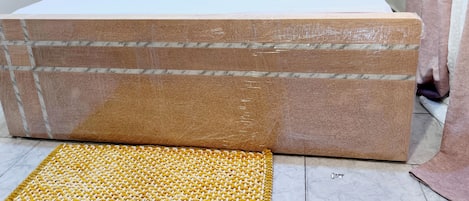Una cama con cabecera de madera, ropa de cama blanca y un tapiz amarillo tejido en el suelo.