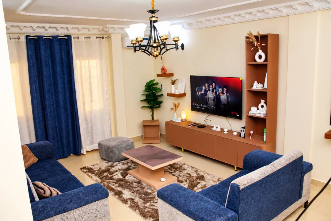 A living room with a sofa set, a coffee table, a TV, and a bookshelf.