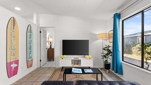 A modern living room with a flat-screen TV, a sofa, a coffee table, and a large window. - POOL/Golf Cart/Hot Tub/Playground/Grill/Arcades (Panama City)