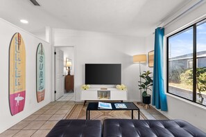 A modern living room with a flat-screen TV, a sofa, a coffee table, and a large window. - POOL/Golf Cart/Hot Tub/Playground/Grill/Arcades (Panama City)