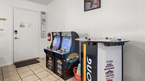 A room with two arcade machines, a ping pong table, and a door with a fire extinguisher. - POOL/Golf Cart/Hot Tub/Playground/Grill/Arcades (Panama City)