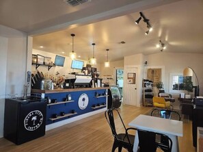 Ein Café-Interieur mit Theke, Sitzbereich und einer Präsentation von Kaffeemaschinen.