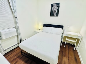 A neatly arranged bedroom with a bed, bedside tables, a desk, and a wall-mounted picture. - Luxe, Bright & Stylish 2Bed Unit w/Parking near NYC! (Haledon)