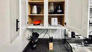 A kitchen with a countertop, a sink, and a cabinet with kitchen appliances.
