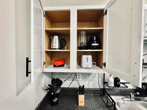 A kitchen with a countertop, a sink, and a cabinet with kitchen appliances.