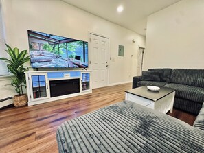 A living room with a flat-screen TV, a sofa, a coffee table, and a potted plant.
