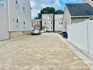 A paved driveway leading to a row of townhouses with a car parked in the middle. - Luxe, Bright & Stylish 2Bed Unit w/Parking near NYC! (Haledon)