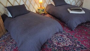 A room with two beds, a patterned carpet, a wooden lattice wall, and a small table with a lamp.