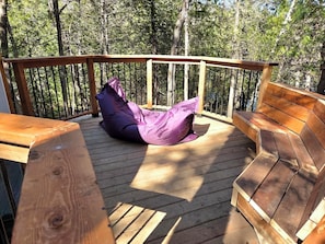 A wooden deck with a bench and a bean bag chair.