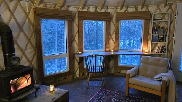 A cozy interior with a wood-burning stove, a chair, a desk with a chair, and a bookshelf.