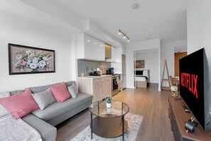 A modern living room with a sofa, coffee table, and a flat-screen TV displaying 'NETFLIX'. - Heart of Downtown - 2BR - Near Dundas Square (Toronto)