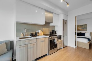 Eine moderne Küche mit Einbauofen, Kühlschrank sowie einem Essbereich mit Tisch und Stühlen.