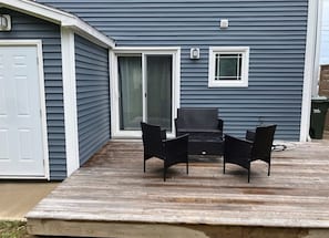 A deck with a table and chairs, a sliding glass door, and a small window.