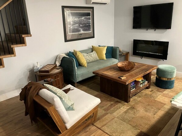 A living room with a sofa, a coffee table, a TV, and a staircase.