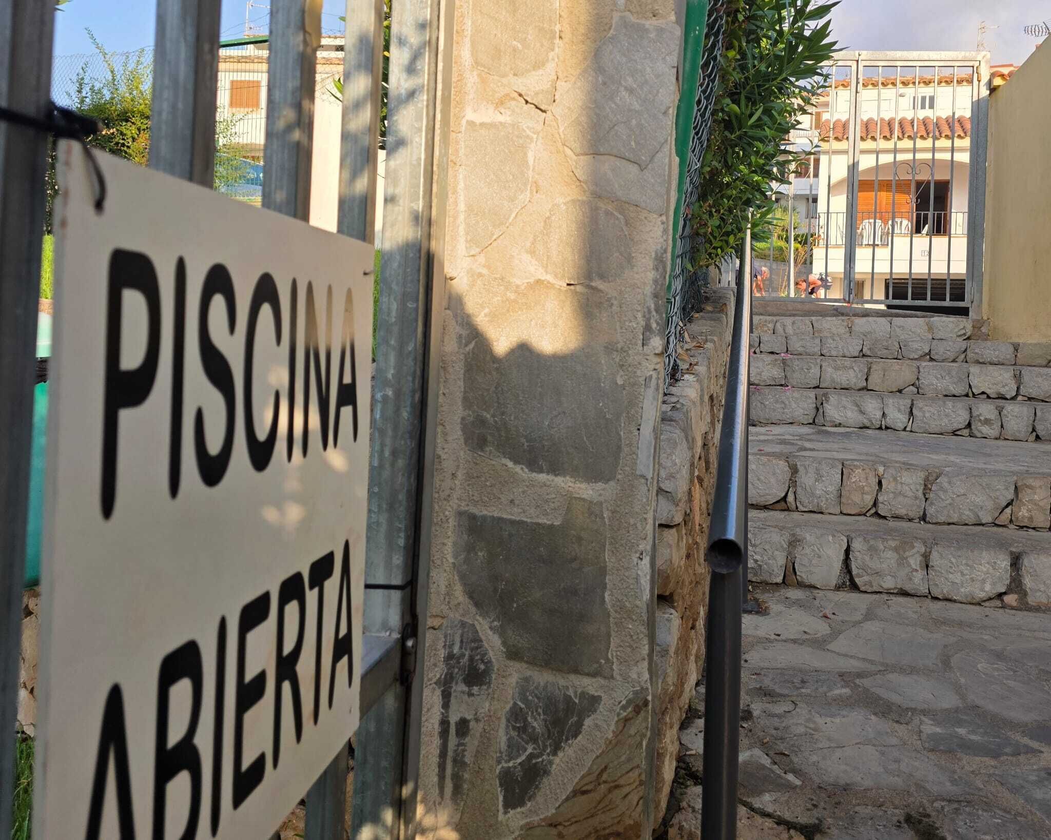 A stone wall with a sign reading 'PISCINA ABIERTA' indicating an open swimming area.