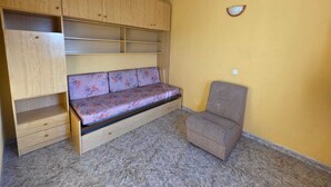 Ein Zimmer mit einer eingebauten hölzernen Sitzbank mit Schubladen, einem karierten Stuhl und einer gelben Wand.