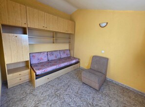 A room with a built-in wooden bench with drawers, a checkered chair, and a yellow wall. - Penisol 12 · 4 bedroom villa with pool (Peñíscola)