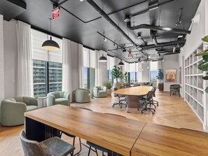 A modern conference room with a large wooden table, comfortable seating, and large windows offering city views. - Bay View Studio - Rooftop Pool - Downtown Miami (Miami)
