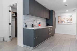 A modern kitchen with grey cabinets, a white countertop, and a tiled backsplash. - *NEW* Lux Condo | High-Floor Views · Gym · Pool · (Miami)
