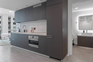 A modern kitchen with grey cabinets, a tiled backsplash, and a built-in oven. - NEW Lux Condo - High-Floor Views · Gym · Pool · (Miami)
